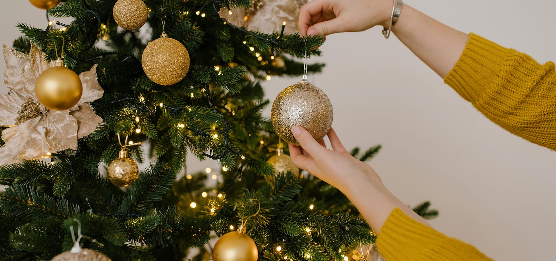Gouden kerstbal wordt opgehangen in kerstboom.