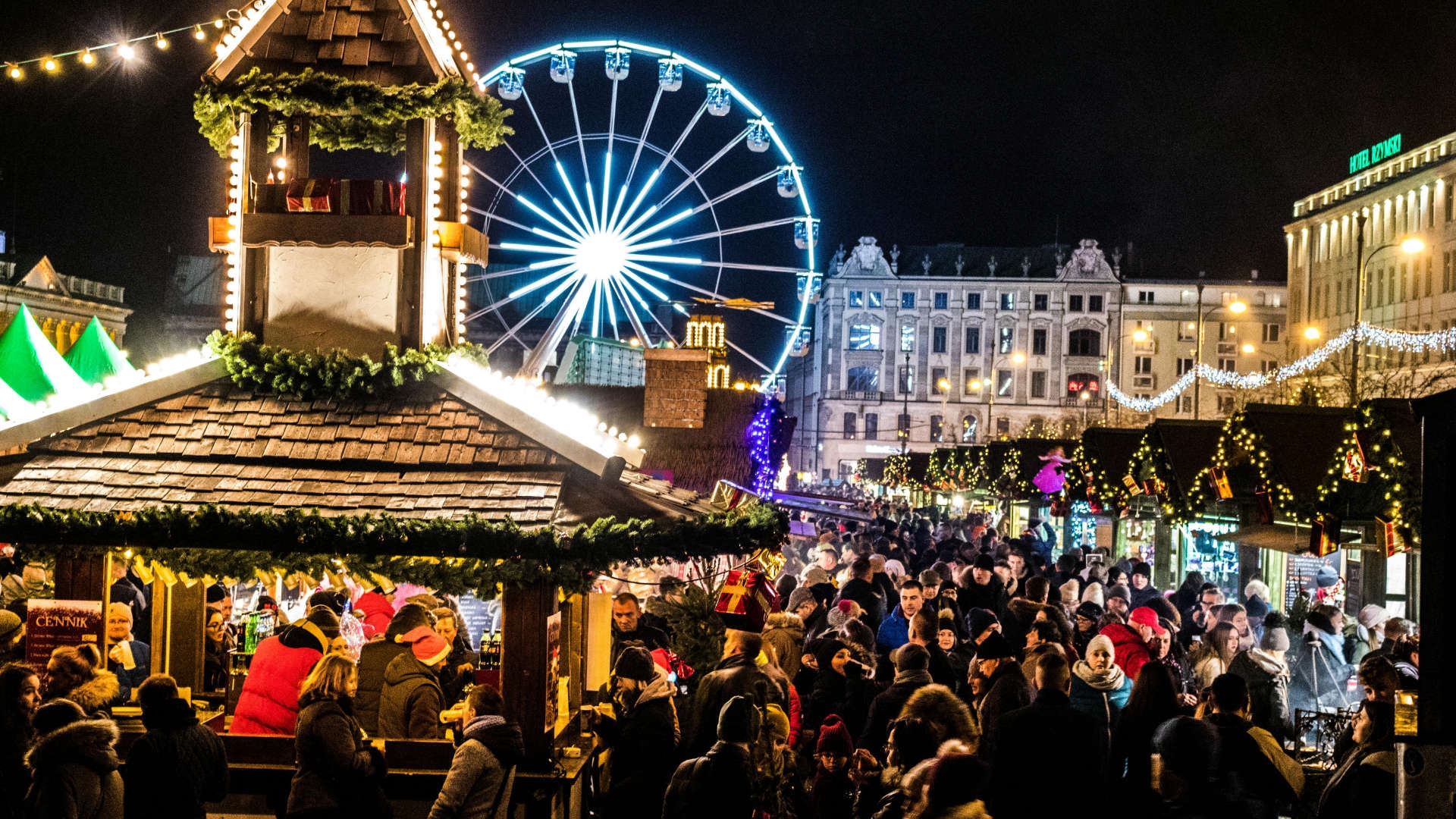Drukke kerstmarkt met lichtjes en bezoekers in de avond