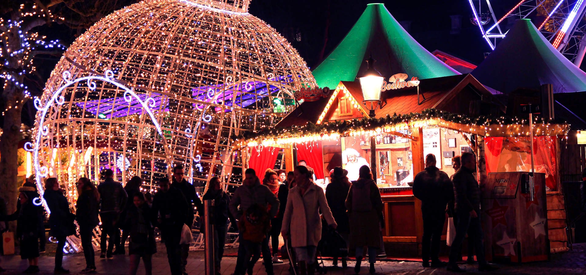 Gezellige kerstmarkt in Maastricht met lichtjes, kraampjes en bezoekers in winterse sfeer.