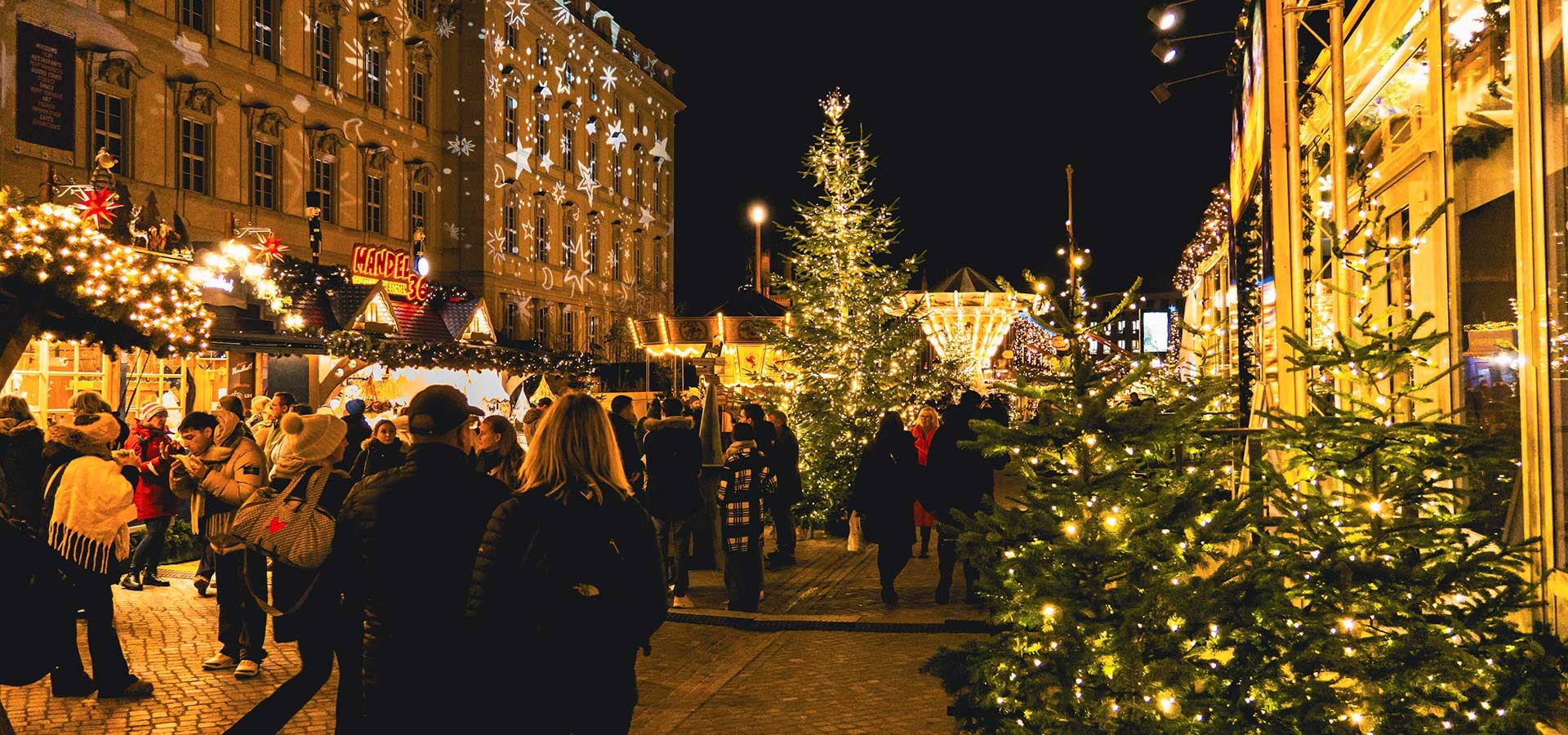 Bezoekers wandelen over een sfeervolle kerstmarkt tijdens een koude winteravond