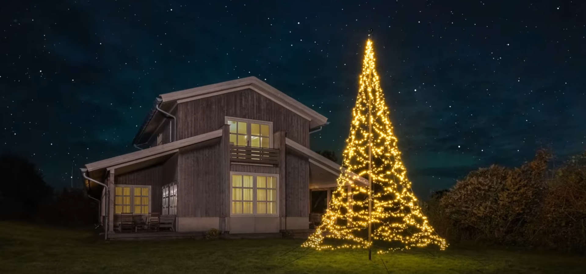 Verlichte vlaggenmast kerstboom buiten tuin