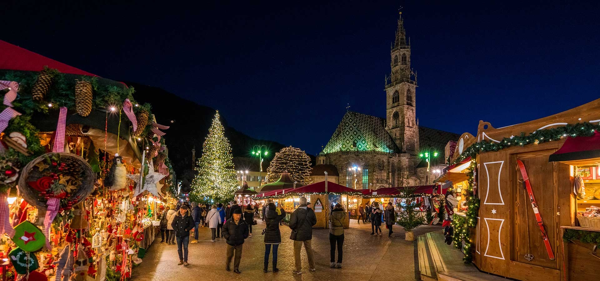 Kerstmarkt in Bolzano met sfeervolle kraampjes en een prachtig verlichte kerstboom op het Waltherplatz
