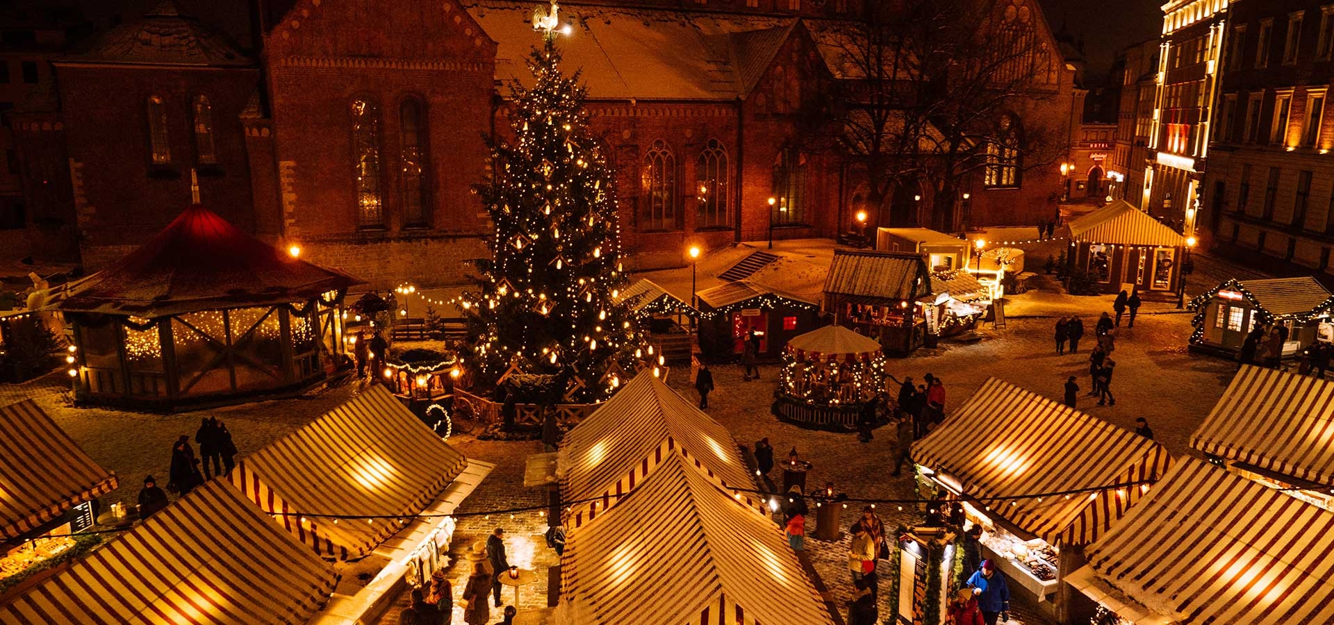 Bezoekers warm gekleed op een kerstmarkt in de avond
